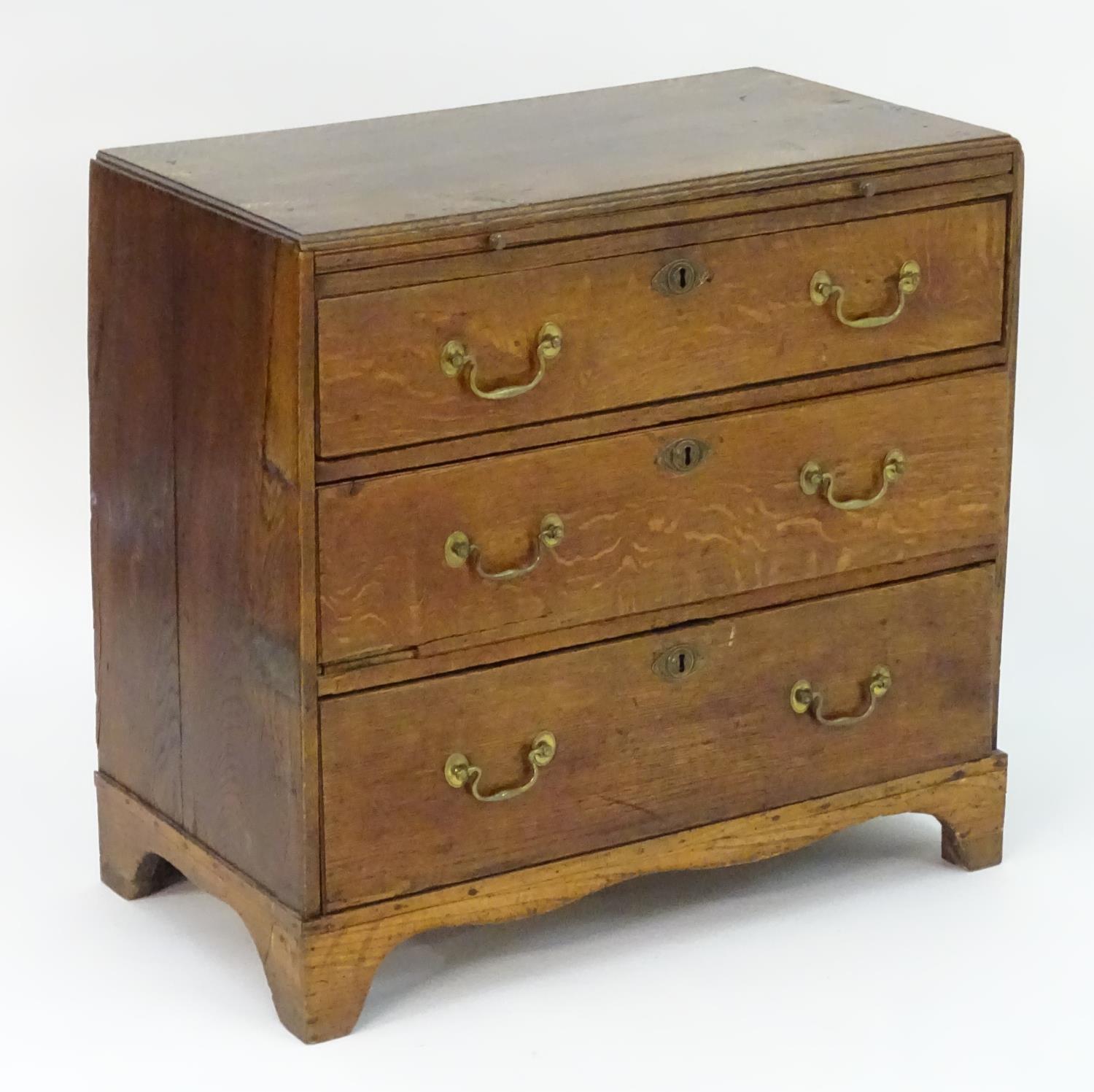 A mid 18thC oak chest of drawers with a rectangular top above a brushing slide and three long