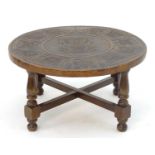 An Andean mohena wood and leather circular coffee table, having four legs with cross struts and a