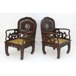 A pair of Chinese hardwood armchairs with pierced and carved backrests, fretwork supports and