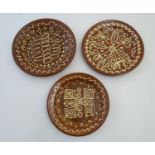 Three 20thC slipware chargers decorated with abstract patterns. One with impressed H maker's mark.
