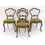 A set of four walnut balloon back dining chairs with needlework upholstered seats and raised on