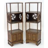 A pair of Chinese bookcases with four tiers supported by turned columns and having panelled cupboard
