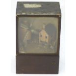 A Victorian diorama display depicting a naive scratch built scene of a windmill and cottage within a