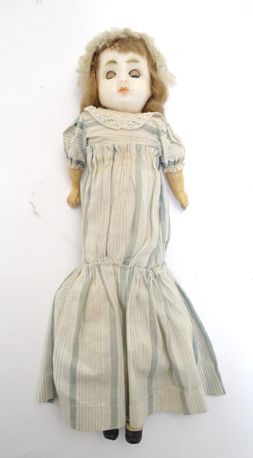 Toy: A wax headed doll with blue eyes, painted features, brown hair, composite forearms and