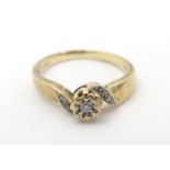 A 9ct gold ring set with central diamond flanked by diamonds to shoulders. Ring size approx J 1/2