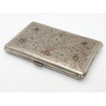A white metal cigarette case, the eastern/ Islamic style decoration having red and green enamel