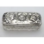 A cut glass dressing table box with silver top having embossed angel decoration. Hallmarked