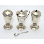An Art Deco silver three piece cruet set comprising salt, pepper and mustard pot (with spoon and