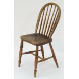 A 19thC elm childs Windsor chair with bowed back and stick supports above a shaped seat and raised