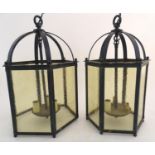 A graduated pair of bronze pendant hall lanterns, of hexagonal form with glazed panels and black