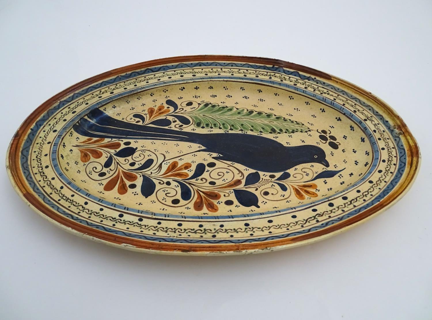 A Swiss terracotta oval pottery dish with hand painted folk art decoration depicting a bird - Image 4 of 6