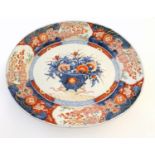 A Japanese Imari style plate, the centre decorated with a vase of flowers with a floral border.