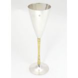 An Elizabeth II silver gilt Stuart Devlin champagne flute having flaring conical body with