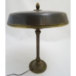 An early 20thC brass table lamp, the circular base decorated with Art Noveau motifs and supporting a