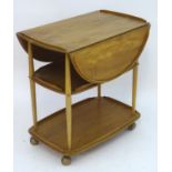 Vintage Retro, Mid-Century: an Ercol elm and beech three tiered trolley, the top with drop flaps,