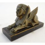 A 20thC paperweight formed as a winged sphinx with the head of a pharaoh on a rectangular wooden