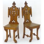 A pair of 19thC oak hall chairs with carved backrests, pierced quatrefoil decoration and a shield to