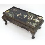 An oriental coffee table with a glass top, the table top depicting figures and scenes, most of the