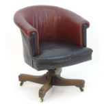 An early 20thC leather swivel armchair with an adjustable backrest and having four mahogany spokes