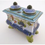 A Continental faience inkwell of sarcophagus form on four paw feet with hand painted floral