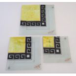 A late-20thC graduated trio of studio art glass plates, each with hand-painted greek key bordering