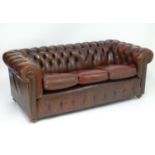 A 20thC oxblood leather Chesterfield three seat sofa, with button back upholstery, scrolled arms and
