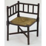 An early 20thC corner chair with a bobbin turned frame above an envelope rush seat and raised on