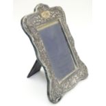 An Art Nouveau photograph frame with silver surround having embossed decoration , on easel style