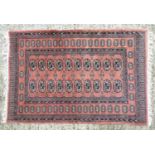 A salmon ground rug decorated with geometric banding and floral vignettes. Approx 60" x 39" Please