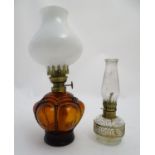 An early 20thC oil table lamp, the amber glass base with internal reservoir and fitted with a milk