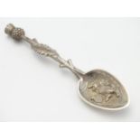 A white metal souvenir spoon with thistle formed handle, lion to bowl and engraved to reverse '
