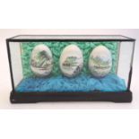 Three 20thC Chinese hand painted eggs depicting Oriental landscapes contained within a glazed