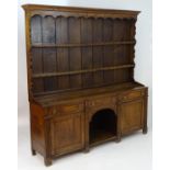 An 18thC oak dresser with a moulded cornice above a shaped frieze and two shelves. The base