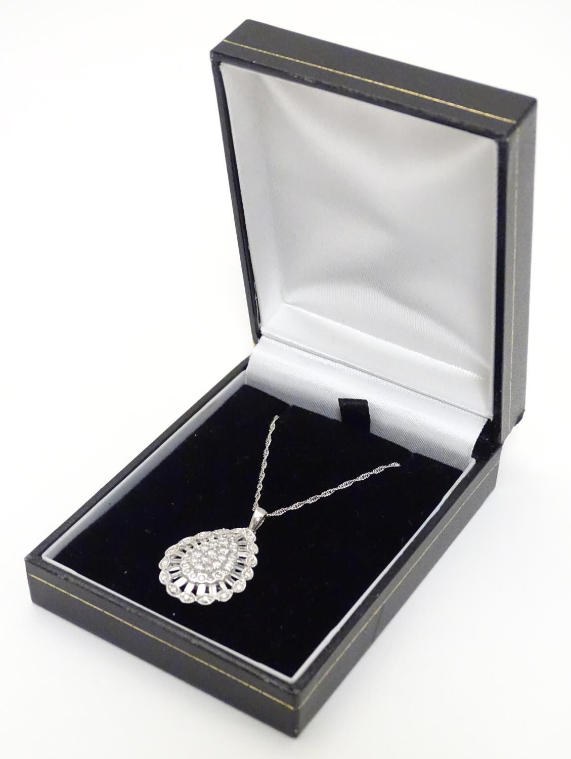 A 9ct white gold pendant set with a profusion of diamonds, on an 18" long and. The pendant approx 1"