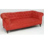 A late 19thC deep buttoned Chesterfield sofa stamped 'Howard' and raised on turned front legs and