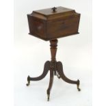 A Regency mahogany tea caddy on stand, with a sarcophagus shaped lid, egg and dart mouldings and