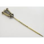 A Vintage Art Deco yellow metal stick pin, the top surmounted by a scrolling serpent decoration. The