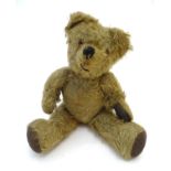 Toy: A mohair teddy bear with articulated limbs and head, pad paws, and a proud, stitched nose.