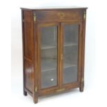 A late 19thC cabinet / bookcase in the Empire style, having a rectangular moulded top above single