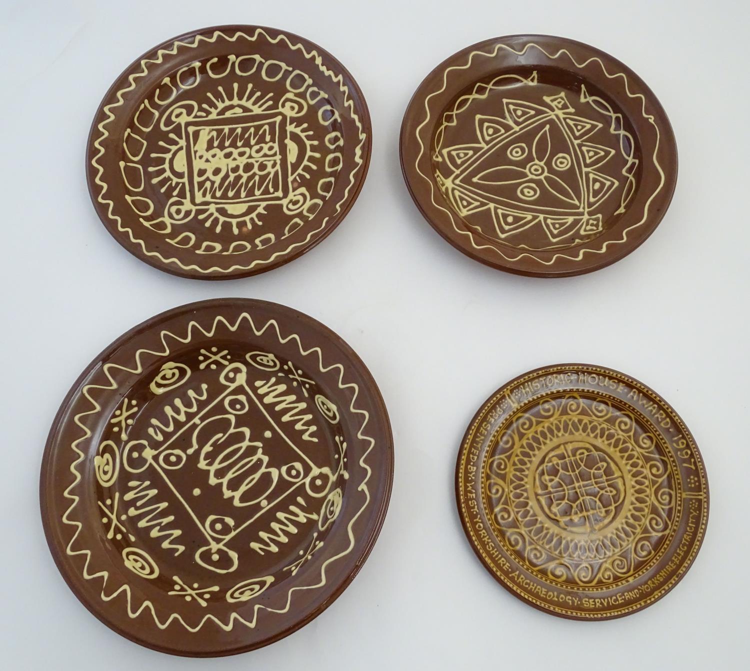Four 20thC slipware chargers decorated with abstract patterns, one with a border bearing Historic