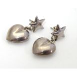A pair of silver and white metal earrings with heart shaped drops below a star. Stamped 925. Approx.