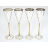 A set of four Elizabeth II silver gilt Stuart Devlin champagne flutes, having flaring conical body