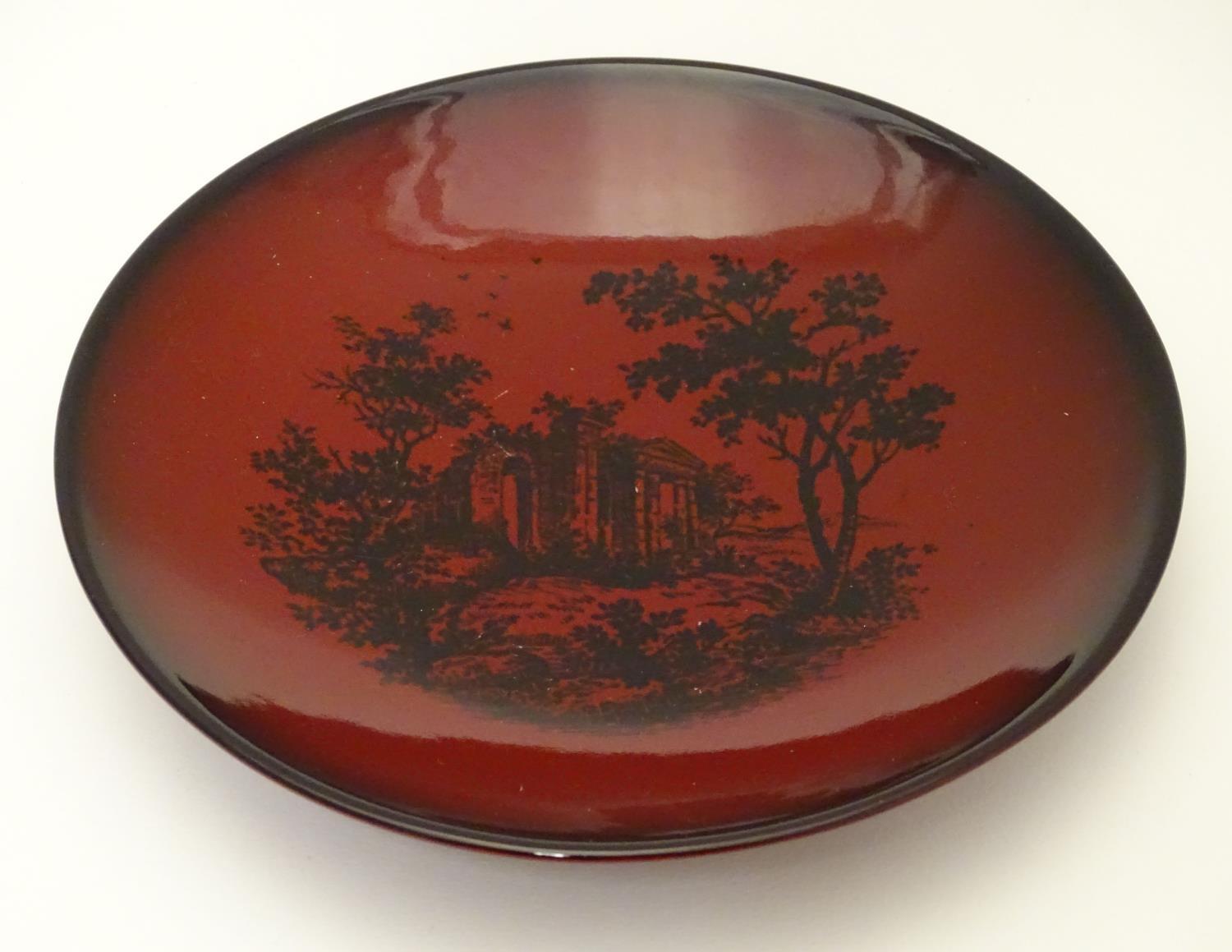 A Royal Doulton flambe dish depicting a wooded landscape with a classical ruin. Marked under Woodcut