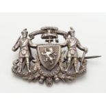 A Scottish silver badge / brooch decorated with figures in highland dress, with shield to centre and