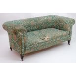 A C1910 Chesterfield sofa with button back upholstery and a sprung seat, the sofa raised on tapering
