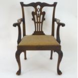 A late 19thC mahogany Chippendale style open armchair, with a carved top rail, back splat and
