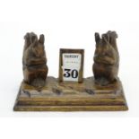 A carved wooden desk calendar and standish / inkwell, the inkwells formed as squirrels eating
