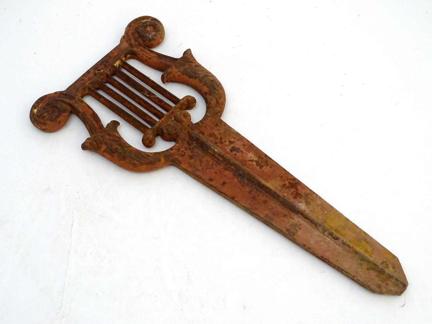 A Victorian cast iron bootscraper, formed as a lyre above a long blade mount, 19" long Please Note -