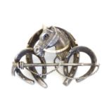 A white metal brooch front. Formed as three horseshoes with horse head and riding crop decoration