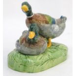 A large ceramic model formed as two ducks on an oval base, one sitting, one standing. Impressed